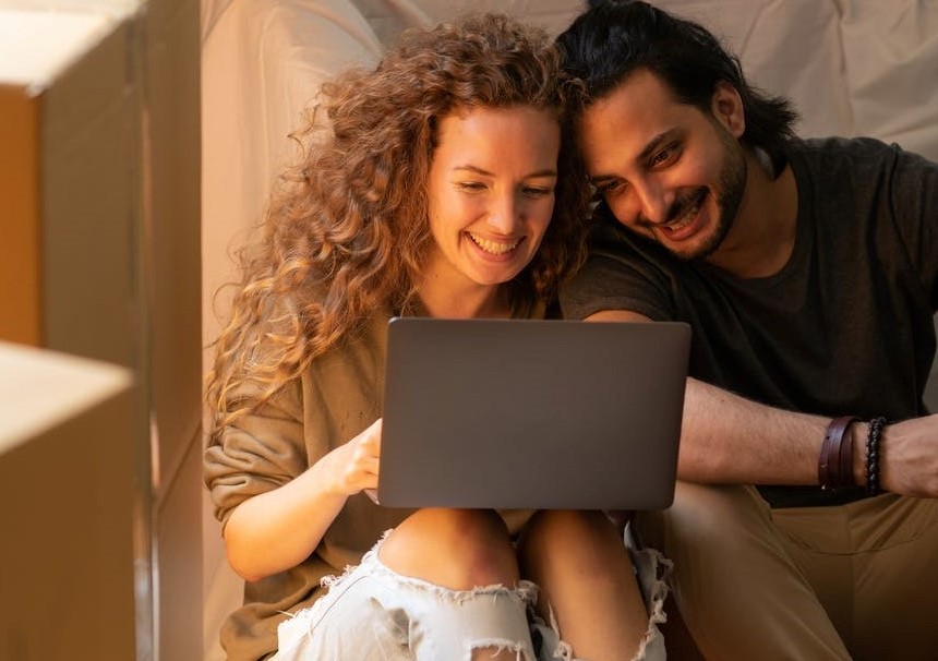 pareja sonriendo frente a laptop