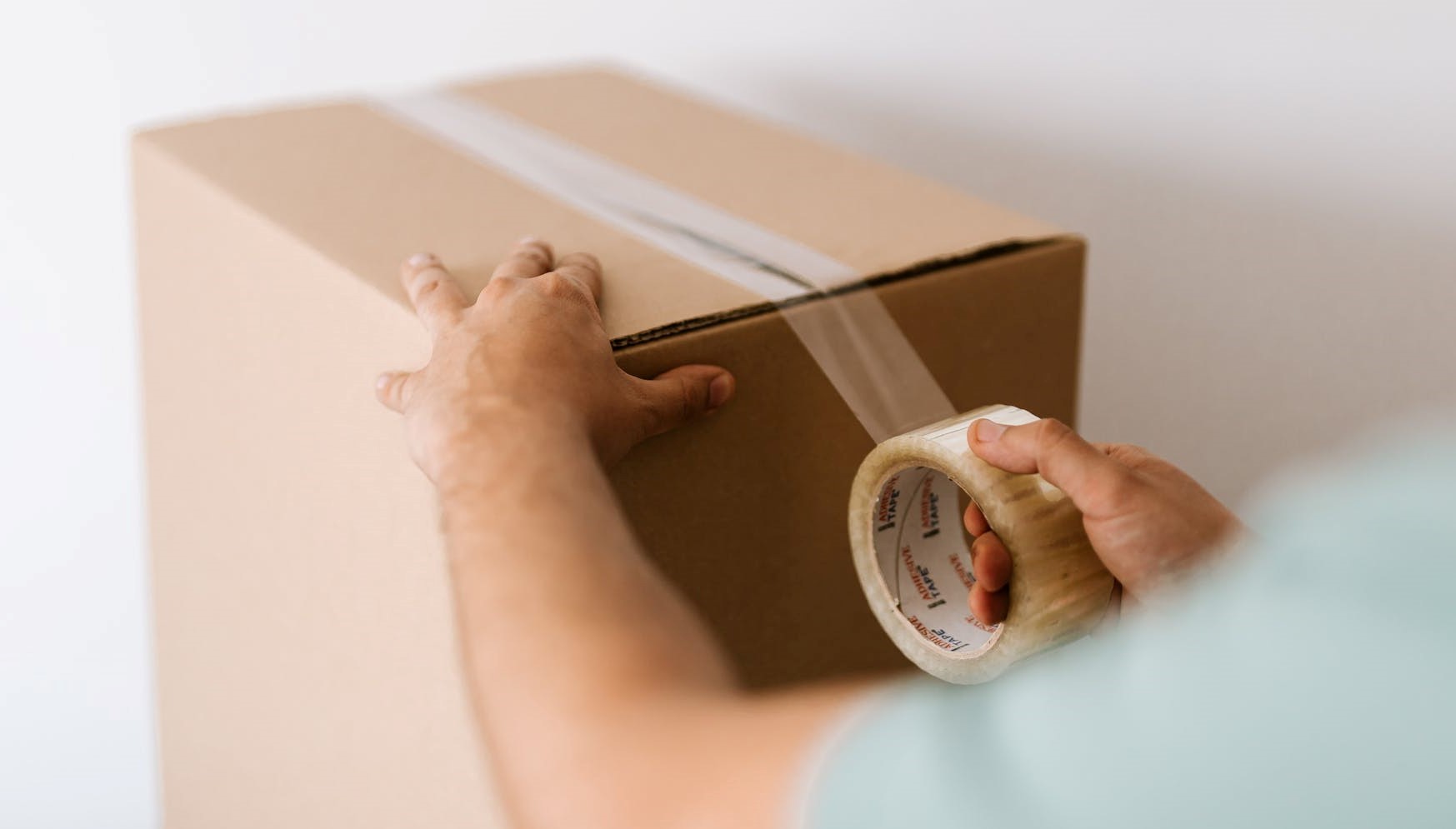hombre sellando una caja de envío con cinta adhesiva